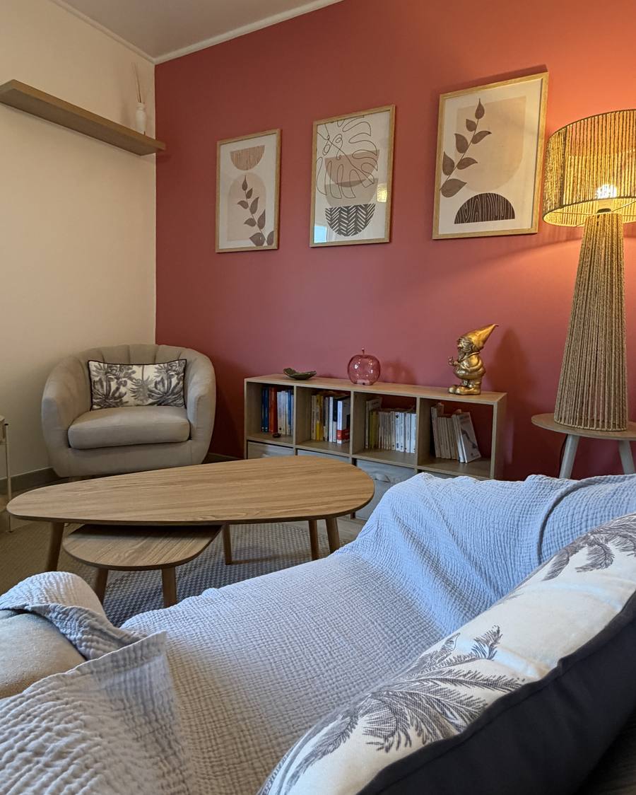 Fauteuil du cabinet devant le mur framboise orné de cadres botaniques
